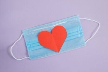 COVID-19. Face mask with cut paper heart on a purple background. Medical masks to protect against viruses and pollution. Concept of celebrating valentine's day in a new reality.