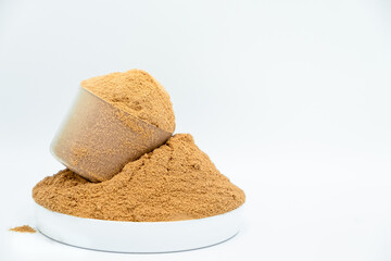 Whey protein powder on white background. Plastic measuring dietary spoon and heap of chocolate shake food drink. Sport workout gym nutrition energy replacement. Exercise muscle body fitness training.