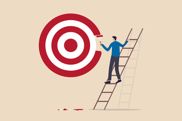 Purpose, set business goal or target, KPI, key performance indicator or set objective and achievement concept, ambitious businessman on ladder using paint roller to paint big dartboard, archery target