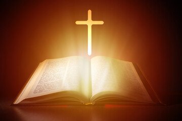 Bible and cross on a dark background. Bright light comes from Christian Bible. Cross next to the open book. Bible study concept. Studying Christian religion Reading religious literature.