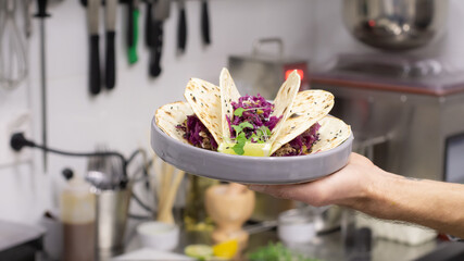 Cooked tacos on a plate in the chef's hand