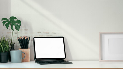 Mockup blank screen tablet with magic keyboard and supplies on wooden table.