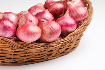 Red onions in wooden basket on white background