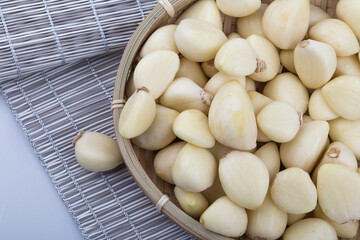 Pile of peeled garlics on basket.