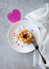 A stack of middle-shaped waffles on a white plate. The background is gray, vertical orientation, top view.