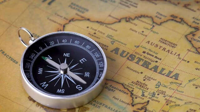 Close up shot of a spinning vintage compass on the ancient map. Concepts of Travel and Instrument for navigation.