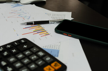 Mobile Phones business documents graphs and chart accounting finance, marketing and reports and pen on desk.