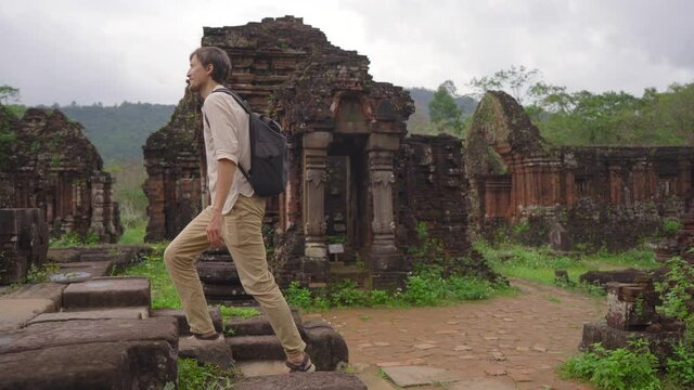 A young man tourist is walking through ruins in the My Son Sanctuary, remains of an ancient Cham civilization in Vietnam.Tourist destination in the city of Danang. Travel to Vietnam concept