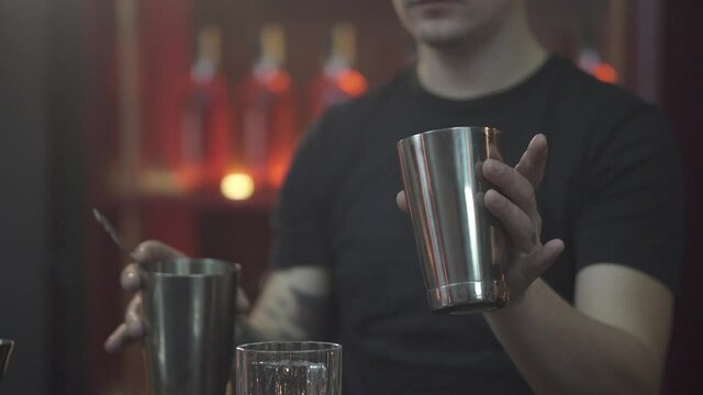 Tattooed Bartender puring the liquid from shaker to shaker