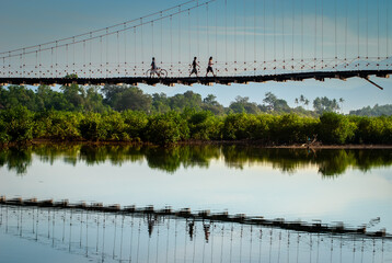 Locals in a rural province crossing a hanging bridge