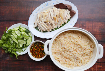 Hainanese Chicken rice - Steamed chicken with oily rice served with cucumber and soy sauce top view on wood table - Thai food called Kao Man Gai 