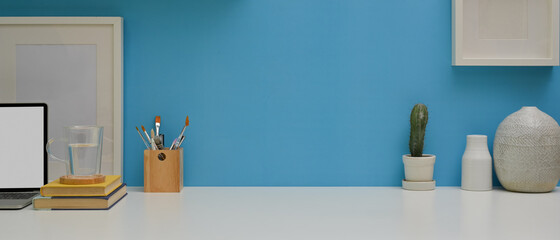 Worktable with laptop, stationery, decorations and copy space in home office room