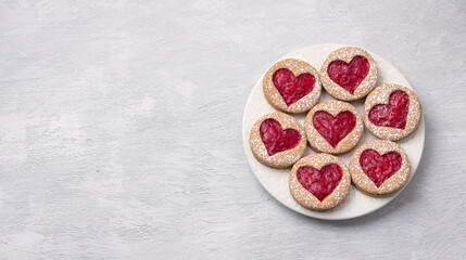 Homemade shortbread spicy cookie with red hearts with jam, on white plate, on gray textured background, for valentine's day. flat lay, space