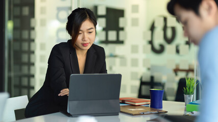 Businesswoman focusing on digital tablet while working with her colleagues