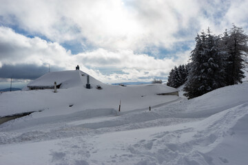 Fototapeta premium Chalet under the snow at Markstein ski resort on a cold partly cloudy day.