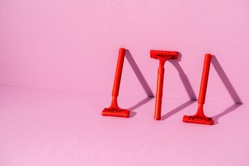 Red disposable razor on pink background, copy space