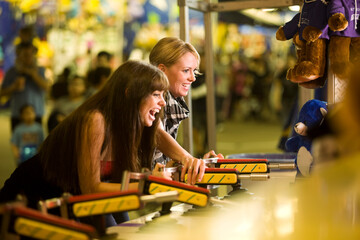 Two female friends playing a game at an amusement park