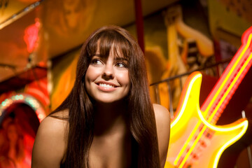 Close-up of a teenage girl smiling in front of a Rock and Roll amusement park ride at night