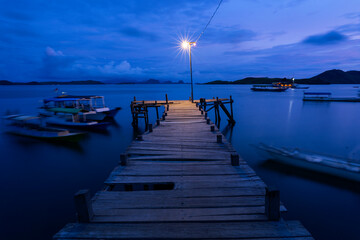 Fototapeta premium pier at dusk with bulp lamp and boats