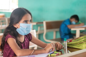 School kid with medical mask listning at classroom - concept of back to school, school reopen with safety measures during coronavirus or covid-19 pandemic.