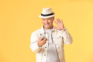 Senior man using mobile phone on color background