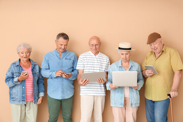 Senior people with different devices near color wall in room