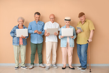 Senior people with different devices near color wall in room
