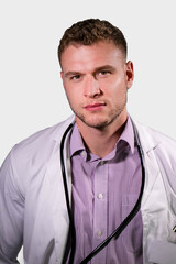 Fototapeta premium Serious handsome male doctor wearing white lab coat looking at camera
