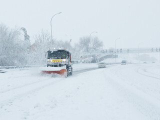 Snow plow truck making way for cars on the highway.