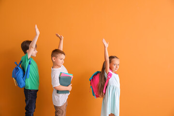 Little children with raised hands on color background