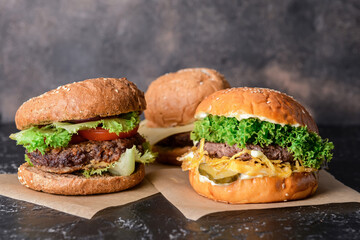 Different tasty burgers on dark background