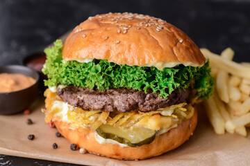 Tasty burger, sauces and french fries on dark background