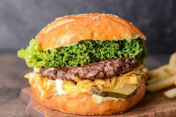 Board with tasty burger on dark background