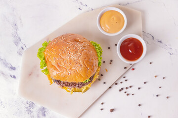 Tasty burger and sauces on light background