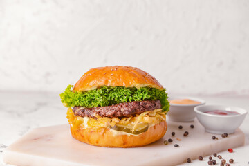 Tasty burger and sauces on light background