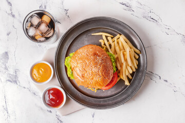 Tray with tasty burger, sauces, french fries and cola drink on light background