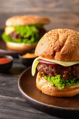 Tasty burgers on dark wooden background, closeup