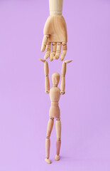 Wooden mannequin and hand on color background