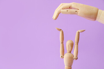 Wooden mannequin and hand on color background