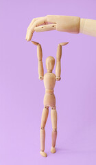 Wooden mannequin and hand on color background