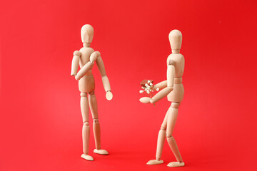Wooden mannequins with flowers on color background