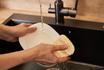 Woman wash dishes with organic eco friendly sponge. Zero waste concept