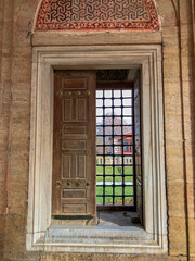 The lead-barred window in the historical mosque and the sunlight penetrating through the window. Wooden inlaid window.