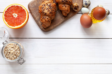 Healthy breakfast with cereal, grapefruit and eggs on wood white background, top view