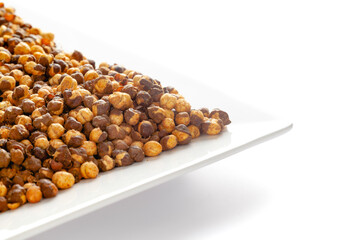 Crunchy Roasted Chana Masala in white ceramic plate, made with Bengal Grams or Chickpeas. Pile of Indian spicy snacks (Namkeen). Side view, against the white background