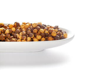 Crunchy Roasted Chana Masala in a white oval bowl, made with Bengal Grams or Chickpeas. Pile of Indian spicy snacks (Namkeen). Side view, against the white background
