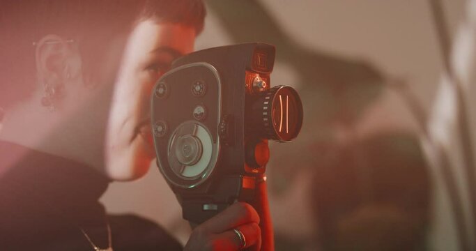 Woman with short hair smiling and filming with a vintage camera 