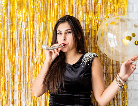 Beautiful Brunette Woman In Black Party Dress Celebrating Her Birthday Blowing The Noise Maker