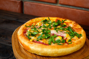 Pizza with cheese, bacon and herbs on a wooden plate. Close-up, selective focus