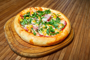 Pizza with cheese, bacon and herbs on a wooden plate. Close-up, selective focus